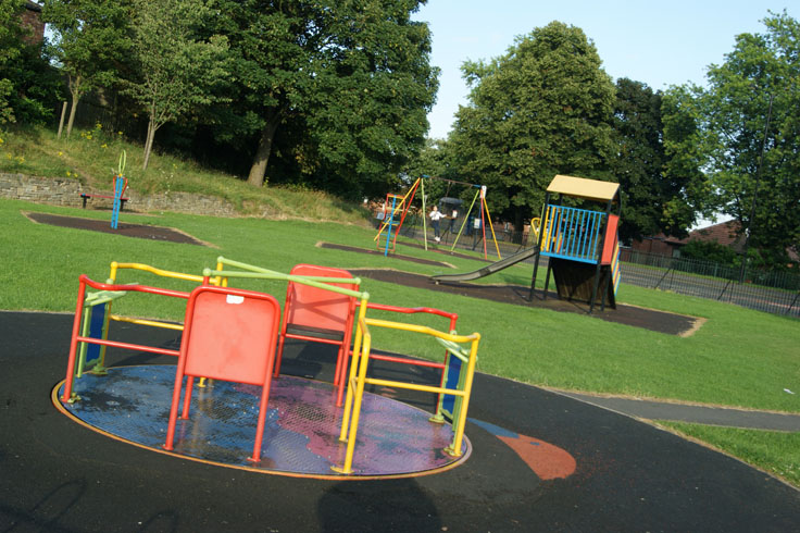 A playground with a girl on the swings.